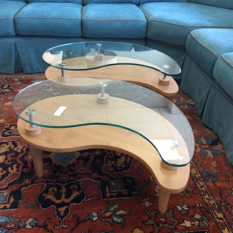 This pair of Midcentury Modern glass top tables are kidney shaped with raised glass tops and a blond wood finish.