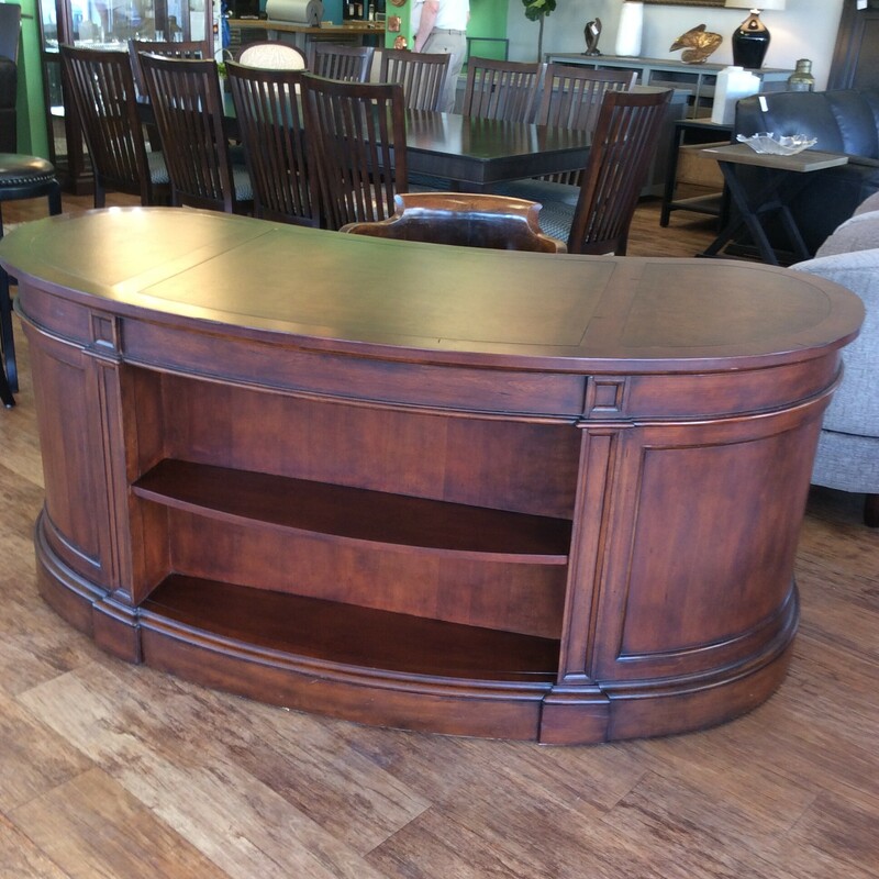 This large kidney shaped desk has a leather desktop and bookshelves in front.