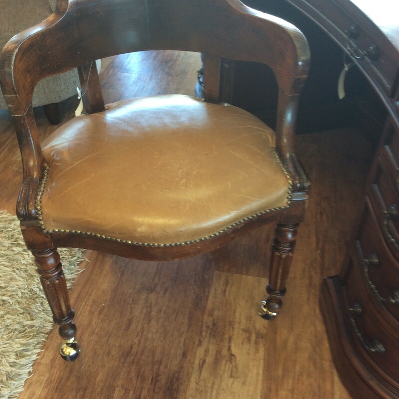This desk chair has a beige leather seat with nailhead trim.