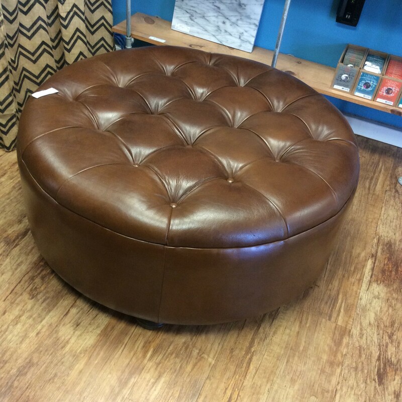This is a beautiful brown, leather tuffed ottoman with brown wood feet.