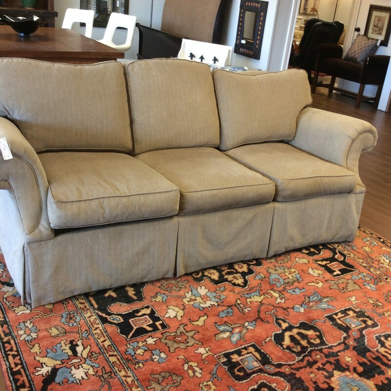 This is a beige Ethan Allen sofa with a skirting wround the bottom.