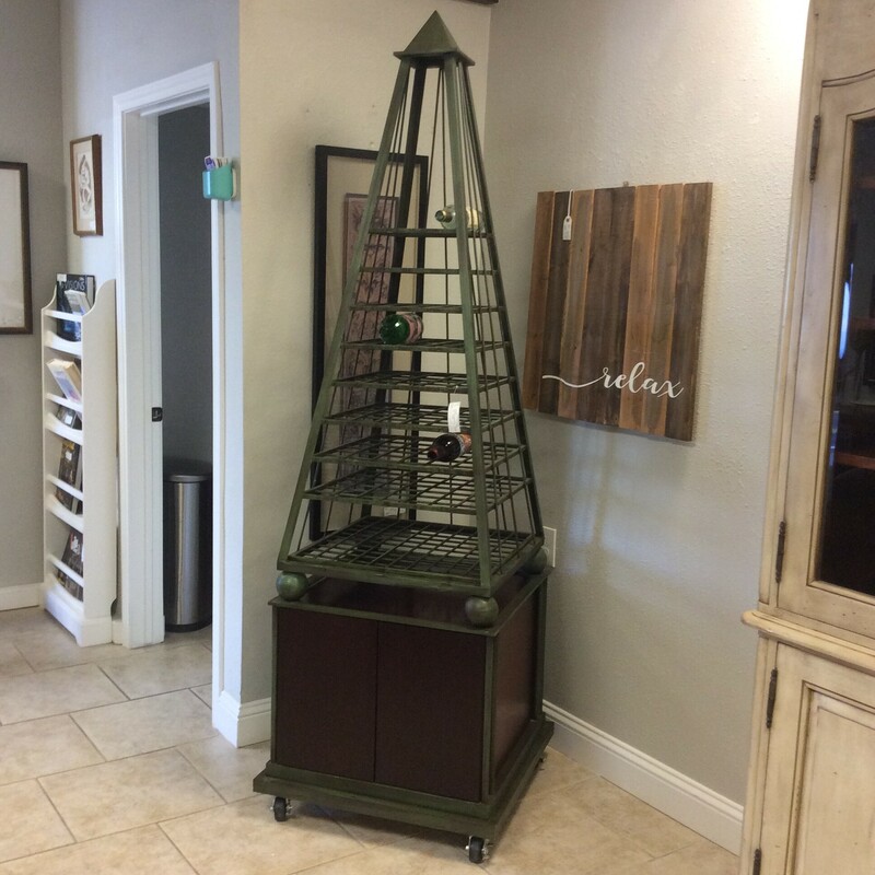This obelisk shaped wine tower is for the serious wine drinker. It has a storage cabinet below with wheels for easy moving.