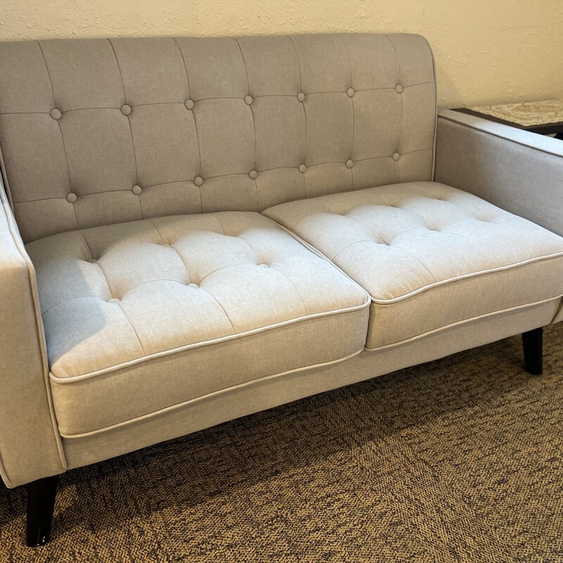 Grey tufted loveseat.

Beautiful light grey fabric loveseat with a tufted back cushion.

Has black wood legs.

There are some scratch marks on the legs.

There are minor stains on the loveseat.

55 1/2in wide x 27 1/2in deep x 32in tall x 18 1/2in tall (seat to floor)