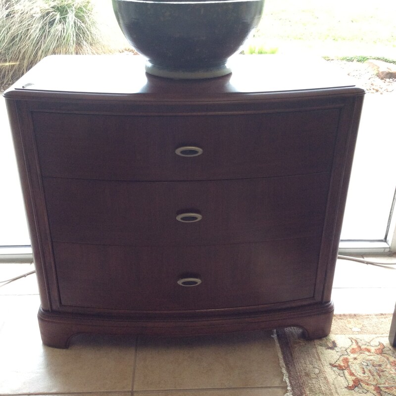 This is a dark wood, 3 drawer night stand with silver hardware.