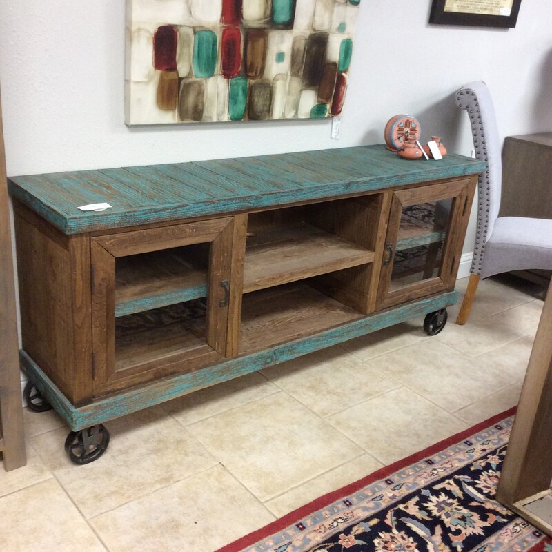 This is a beautiful, teal distrested on dark wood, media cabinet. This cabinet has 2 cabinet glass doors and 1 shelf for your media needs. This cabinet also has industrial wheels for easy to move.