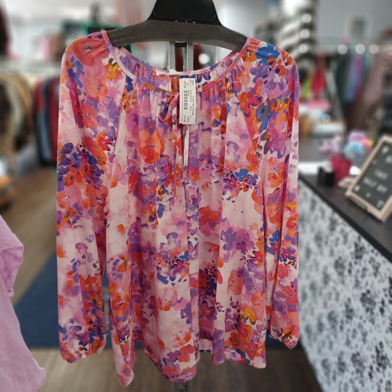 This beautiful blouse has a background of light pink with a floral design in pinks, purple, blue and orange. A cute little tie at the neck line and elastic cuffed sleeves give this the versatility to be dressed up or down. Brand new with tags by Adyson Parker
