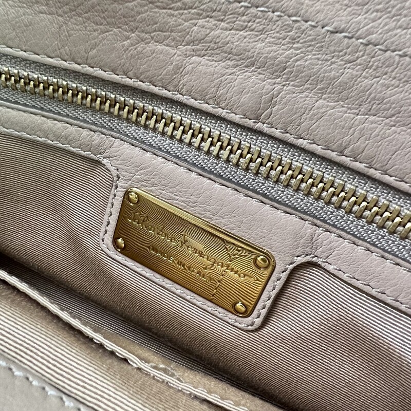 FERRAGAMO<br />
Gancini Pocket Chain Bowler Bag Leather Medium<br />
<br />
Designer: Salvatore Ferragamo<br />
Dimensions: Height: 9.5 in (24.13 cm)Width: 13 in (33.02 cm)Depth: 5 in (12.7 cm)<br />
Period: 21st Century<br />
Material Notes:<br />
Exterior Material: Leather Exterior Color: Beige<br />
Interior Material: Fabric Interior Color: Beige<br />
COMES WITH CERTIFICATE OF AUTHENTICITY<br />
<br />
About the Designer:<br />
Salvatore Ferragamo Clothing<br />
A perfectionist who as a child crafted a pair of white shoes for his sister’s first holy communion because his parents couldn’t afford new footwear, Salvatore Ferragamo was ambitious from his earliest days. The young Italian shoemaker established in the years that followed what would one day become a fashion empire — the highly profitable multinational family-owned and -operated luxury brand today counts more than 600 stores in 96 countries around the world, and vintage Salvatore Ferragamo shoes, belts, handbags and other clothing and accessories are objects of desire for fashion lovers everywhere.<br />
<br />
Salvatore Ferragamo sought an education in the art of shoemaking when he was eleven — he apprenticed with a local shoemaker and spent a short time in nearby Naples learning what he could at a shoe factory. He opened his first shop with a handful of workers the following year, and in 1914 — when he was still a teenager — Ferragamo emigrated to America, just as his siblings had before him, seeking new opportunities for work and to learn in the footwear trade.<br />
<br />
After securing a job at the Plant Shoe Factory in Boston, Massachusetts, Ferragamo was uninspired by machine-made footwear. He moved across the country to Santa Barbara, California. Owing to a connection he made with a then-actor cousin, Ferragamo found work with the American Film Manufacturing Company. He made women’s shoes and provided durable cowboy boots for a film crew’s costuming department. Ferragamo’s reputation in the world of Hollywood cinema soon broadened, and he established a storefront in Mission Canyon where he made shoes by hand for the likes of actresses Gloria Swanson, Greta Garbo and Dolores del Río.<br />
<br />
By the 1920s, film directors commissioned Ferragamo to produce shoes for a range of movies — the list of films eventually included The Ten Commandments, The Covered Wagon and The Thief of Baghdad. When he felt comfortable enough with the English language, Ferragamo also enrolled in anatomy courses at the University of Southern California in Los Angeles in order to better understand motion and the demands that we place on our footwear.<br />
<br />
By the late 1920s, Ferragamo sought to expand production of his shoes and returned to Italy. He hired scores of apprentices to work in a factory in Florence, where Ferragamo carefully melded the principles of handcraftsmanship with all that he learned about America’s shoe factories. He filed patents — hundreds over the years — on the steel shank arch and many other unique aspects of his shoe design, and when economic and political influences during the 1930s forced Ferragamo to substitute pressed cork for steel to support the arch, the wedge heel was born. Other creative materials he integrated into his forward-looking creations were hemp, felt, nylon fishing line, fish skin and cellophane twisted with silk.<br />
<br />
In the late 1940s, the brand’s first storefront opened in Manhattan, and today Salvatore Ferragamo is known worldwide and is synonymous with a wealth of iconic footwear such as Viva ballet flats, Vara Bow pumps, Gancini loafers and lots more. Ferragamo’s son, Ferruccio, was appointed CEO in 1984. Under his leadership, Ferruccio diversified and expanded the fashion business further, getting into sunglasses, fragrance, watches and made-to-measure men’s shoes. Ferruccio was succeeded by his brother, Leonardo Ferragamo, and British designer Maximilian Davis is now creative director of the brand.