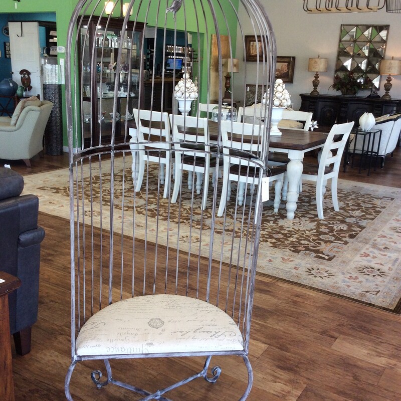 This unique and unusual chair has a metal frame in the shape of a bird cage with an upholstered cushion seat.