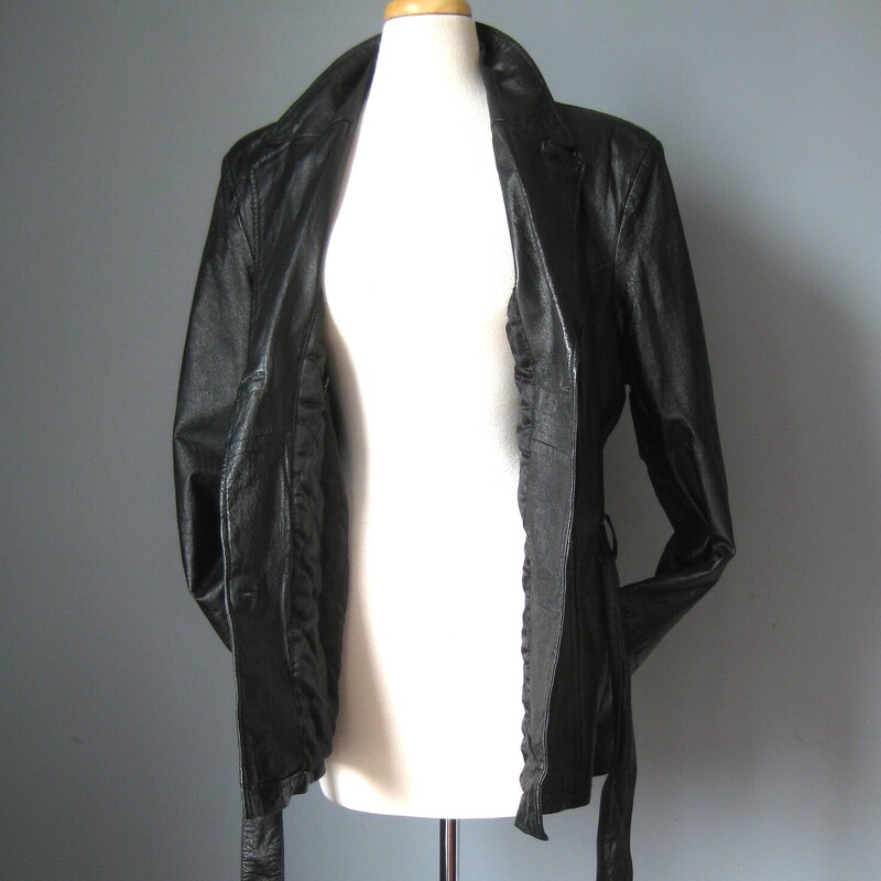 This simple hip length double breasted black leather trench coat has an attached belt, button closures<br />
It has pockets, a cool notched lapel<br />
<br />
Fully lined with a medium weight quilted fabric for a bit of warmth. (no batting)<br />
It has pretty big shoulder pads built in under the lining.<br />
<br />
Excellent condition!<br />
<br />
Here are the flat measurements:<br />
<br />
Armpit to armpit: 23<br />
Width at hem: 22<br />
Length: 28<br />
underarm sleeve seam: 15.5<br />
<br />
Thanks for looking!<br />
#54011