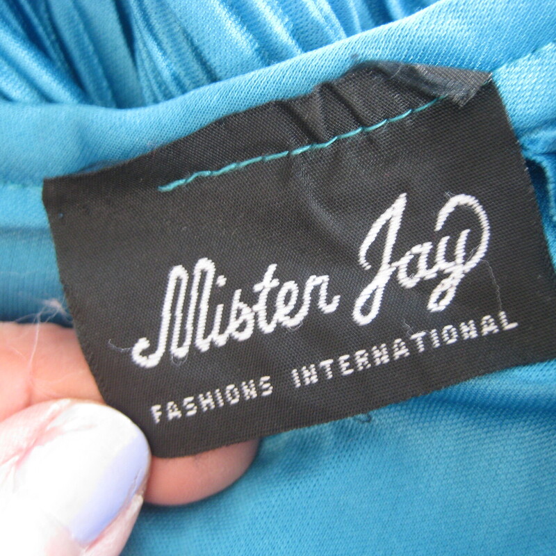 Vtg Mister Jay Gown, Blue, Size: XL<br />
<br />
This fun dress looks like a two piece set but it is one piece<br />
The bodice is micropleated and tunic length with long sleeves.  The bottom edge is free and is adorned with a large fabric flower.<br />
The dress underneath is unlined, unpleated and has an elastic waist<br />
Small shoulder pads, more to support the weight of the gown that to add to the silhouette.<br />
the sleeve ends are gathered and elasticized.<br />
somewhat stretchy polyester<br />
by Mr. Jay<br />
<br />
No size tags<br />
flat measurements:<br />
Shoulder to shoulder: 16<br />
armpit to armpit: 23<br />
waist: 13.5 stretches comfortably to 17<br />
hip: free<br />
length: 53<br />
underarm sleeve seam length: 16.5<br />
<br />
<br />
Thanks for looking!<br />
#46136