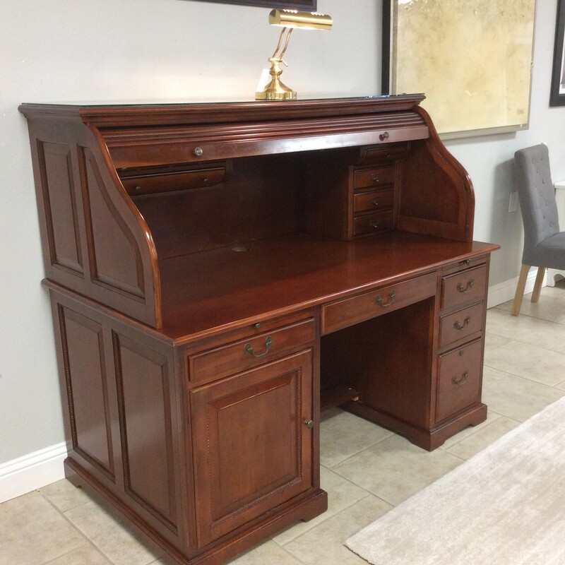 This is a gorgeous rolltop desk! And it's well priced too! Traditional in style like the ones we've been used to over the decades it offers all the features that we love but also accomodates today's technology needs. There are multiple small drawers and cubbies, a file cabinet drawer, 2 pull-out trays, space for a tower, holds a keyboard and more. The wood finish is a gorgeous rich brown with hardly a scratch and even includes a glass top. This is in pristeen condition and it includes a unique feature - the back is finished. You don't see that often, take that as a sign of quality craftsmanship. It's going to look beautiful against a wall or floating. These go very quickly here, so come on  in and take a look.