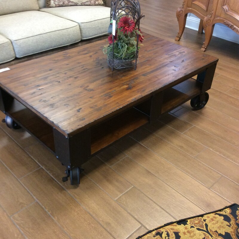 This rustic, industrial cart, coffee table by Maverick has a distressed pine top with metal wheels.