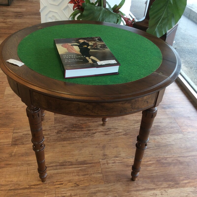 This round antique game table has carved spindle legs with a felt inlaid top.