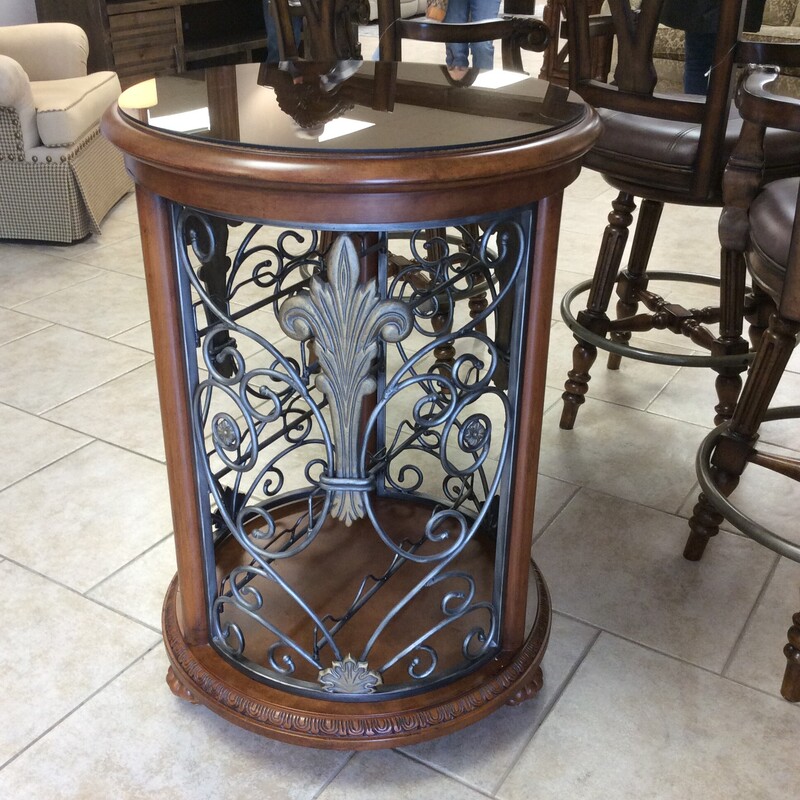 This round glass topped wine storage cabinet has open metal work sides with interior wine storage.