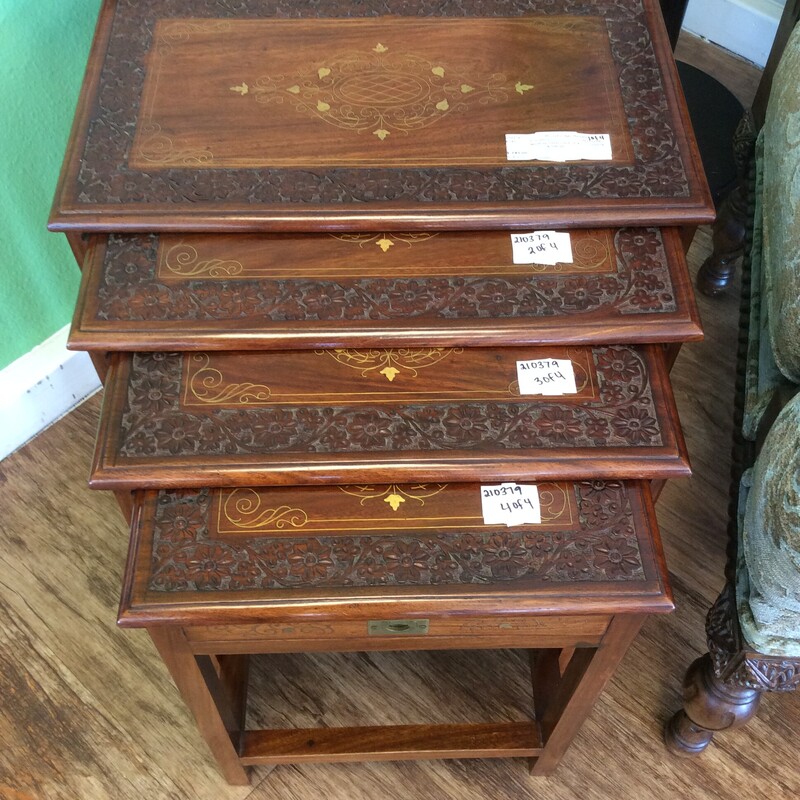 This is a lovely set of 4 nesting tables. They feature a dark wood finish with carved details and painted embellishments on the top. The smallest table in the set features a tiny drawer.