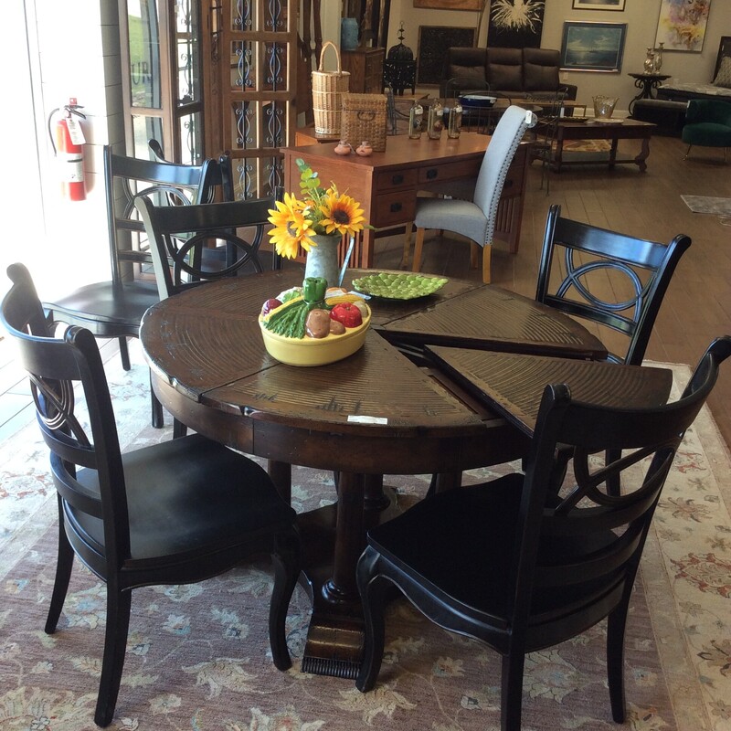 This pie table with 6 chairs is gorgeous! Also known as a Jupe table it's a quality, solid circular diningroom table veneered in finely figured segments and supported on turned legs leading to the trestle-type base. The \"pie slices\" allow the table to contract or expand. The finish is rough-hewn giving it a well-worn, weathered, timeless appeal, you could even call it rustic. The 6 chairs are from Hooker Furniture and are simple in style - a perfect contrast to the table.