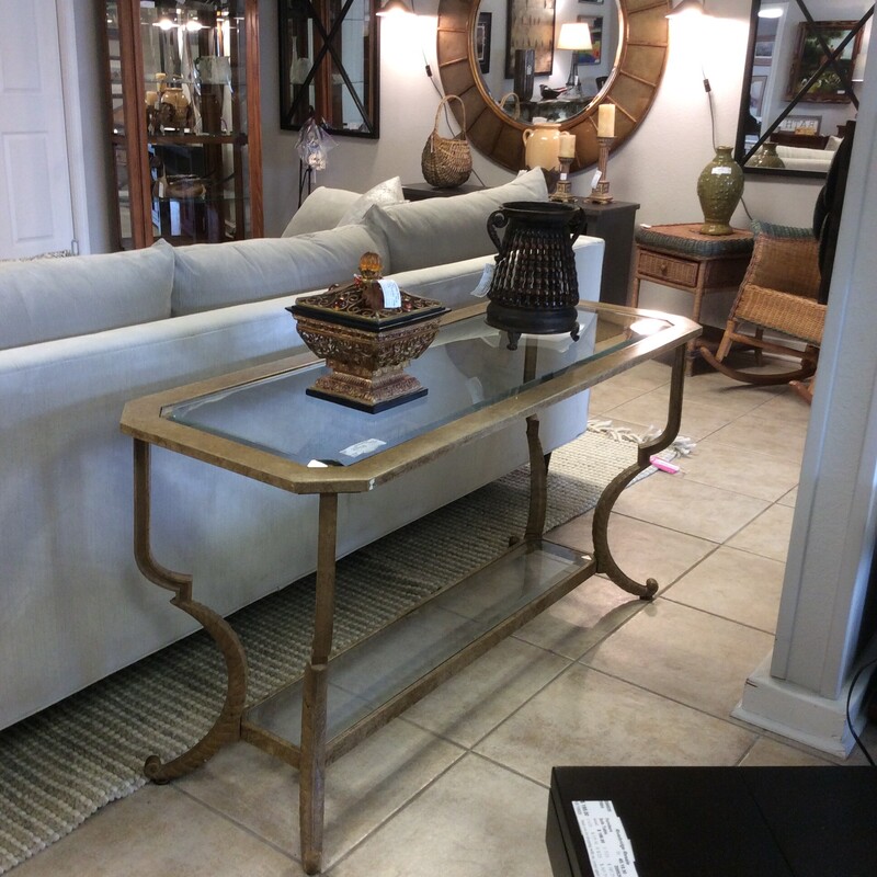 This nice sofa table is modern in design featuring cool, sleek lines. It is 2-tiered and the tabletop is beveled glass. The metal frame has been painted gold.
