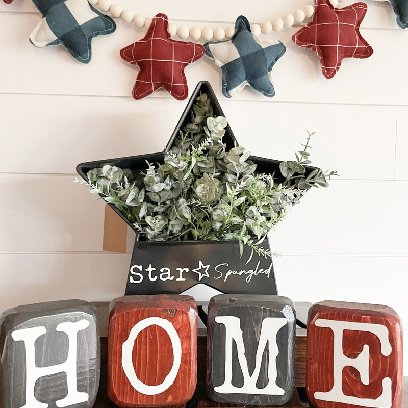 Black Metal Star Planter with Star Spangled Details and Faux Eucalyptus. Measures approximately 8' tall by 3' deep.