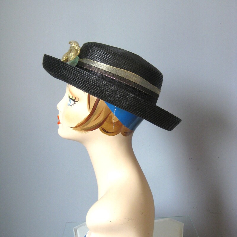 Tailored hat with a turned up brim and a flat top  in black straw with a gold ribbon around the crown finished with a pretty flower made of gold net.
by Saratoga Track hats.
inner hat band measures 21 around.
Excellent condition!

Thanks for looking!!!
#3109

For safety this hat, while very lightweight itself, will have to be shipped in a box, so the shipping on this item, which is built into the price is unfortunately a bit high.