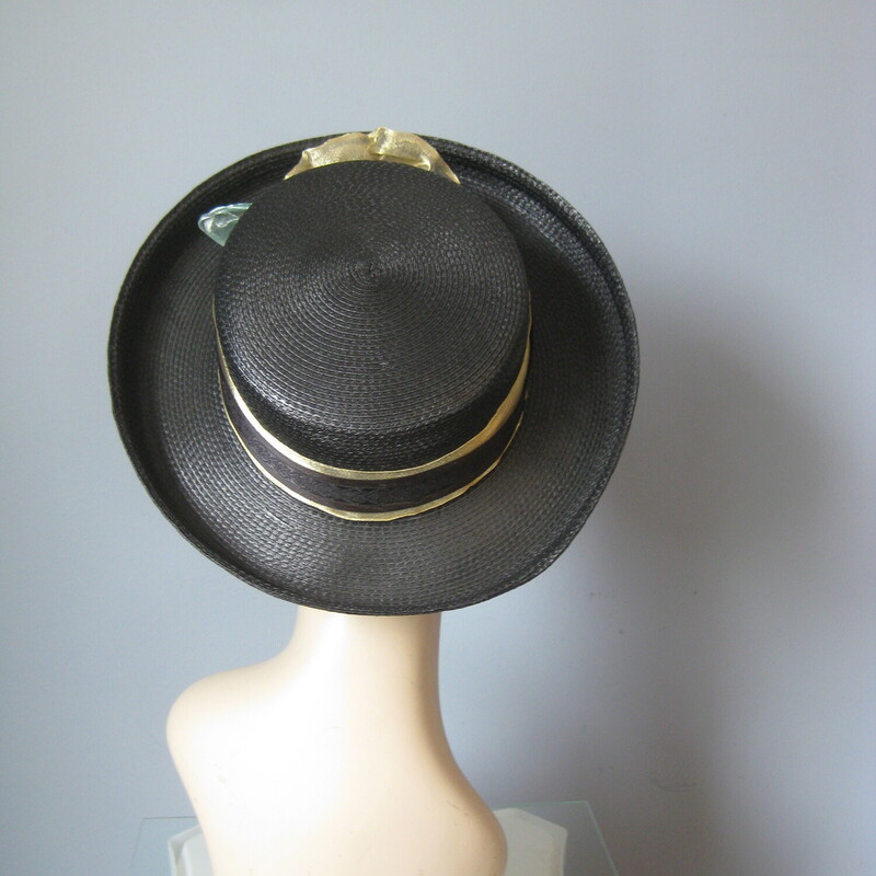 Tailored hat with a turned up brim and a flat top  in black straw with a gold ribbon around the crown finished with a pretty flower made of gold net.<br />
by Saratoga Track hats.<br />
inner hat band measures 21 around.<br />
Excellent condition!<br />
<br />
Thanks for looking!!!<br />
#3109<br />
<br />
For safety this hat, while very lightweight itself, will have to be shipped in a box, so the shipping on this item, which is built into the price is unfortunately a bit high.