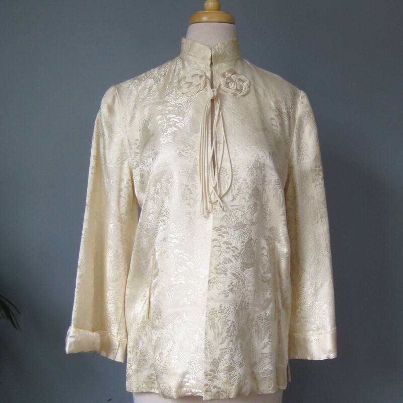 Vtg Satin Traditional, Cream, Size: Medium
This is an off white satin brocade jacket from China.
Quite simple with 3/4 length bell sleeves.
The fabric is a beautiful jacquard with images of mountains and botanics
There is a frog at the neck with closes tne jacket by tying the trailing strings.
It also has a hook and eye at the neck
pockets
marked size M but no other labels.
Probably better for a modern size small
Here are the flat measurements, please double where appropriate:
shoulder to shoulder: 15.5
Armpit to armpit: 19
Length: 26.5
very good condition with some light rust stains as shown .  One is near the hem in the front and one is on the back of one shouldert

Thanks for looking!
#57332
