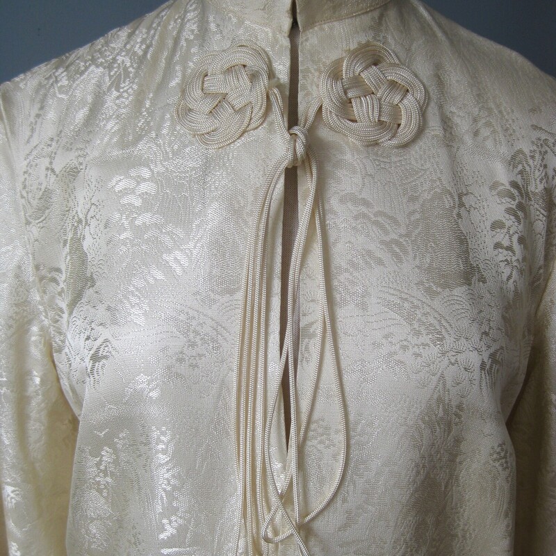 Vtg Satin Traditional, Cream, Size: Medium<br />
This is an off white satin brocade jacket from China.<br />
Quite simple with 3/4 length bell sleeves.<br />
The fabric is a beautiful jacquard with images of mountains and botanics<br />
There is a frog at the neck with closes tne jacket by tying the trailing strings.<br />
It also has a hook and eye at the neck<br />
pockets<br />
marked size M but no other labels.<br />
Probably better for a modern size small<br />
Here are the flat measurements, please double where appropriate:<br />
shoulder to shoulder: 15.5<br />
Armpit to armpit: 19<br />
Length: 26.5<br />
very good condition with some light rust stains as shown .  One is near the hem in the front and one is on the back of one shouldert<br />
<br />
Thanks for looking!<br />
#57332