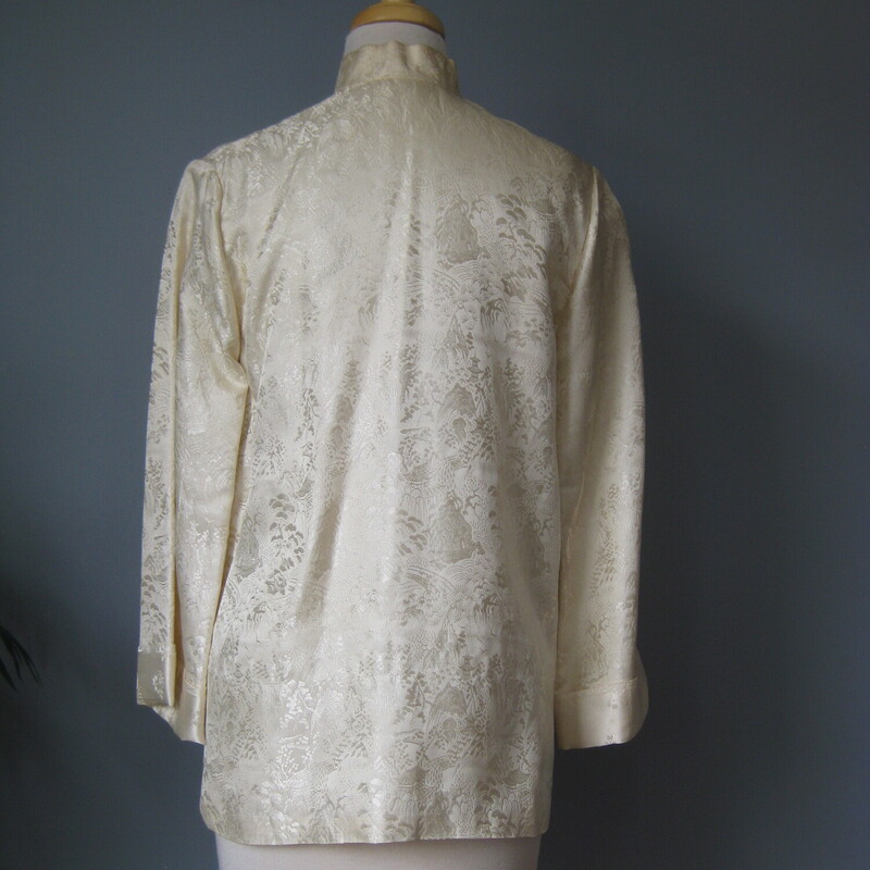 Vtg Satin Traditional, Cream, Size: Medium<br />
This is an off white satin brocade jacket from China.<br />
Quite simple with 3/4 length bell sleeves.<br />
The fabric is a beautiful jacquard with images of mountains and botanics<br />
There is a frog at the neck with closes tne jacket by tying the trailing strings.<br />
It also has a hook and eye at the neck<br />
pockets<br />
marked size M but no other labels.<br />
Probably better for a modern size small<br />
Here are the flat measurements, please double where appropriate:<br />
shoulder to shoulder: 15.5<br />
Armpit to armpit: 19<br />
Length: 26.5<br />
very good condition with some light rust stains as shown .  One is near the hem in the front and one is on the back of one shouldert<br />
<br />
Thanks for looking!<br />
#57332