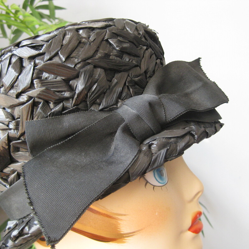 Cloche hats are naturally dramatic and coquettish.<br />
This one is made of black cellophane straw.<br />
There is a wide grosgrain ribbon encircling the crown finished with a large bow.<br />
<br />
<br />
Excellent condition!<br />
Inner hat band measures 201/4<br />
<br />
You want this hat to sit low on your head so if you don't already know, do wrap a tape measure around your head to see where the hat is going to sit on you and make sure you're happy with that.<br />
<br />
Thanks for looking!<br />
#62834