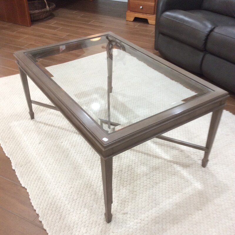 This coffee table has abeveled glass inser with a grey wood finish.