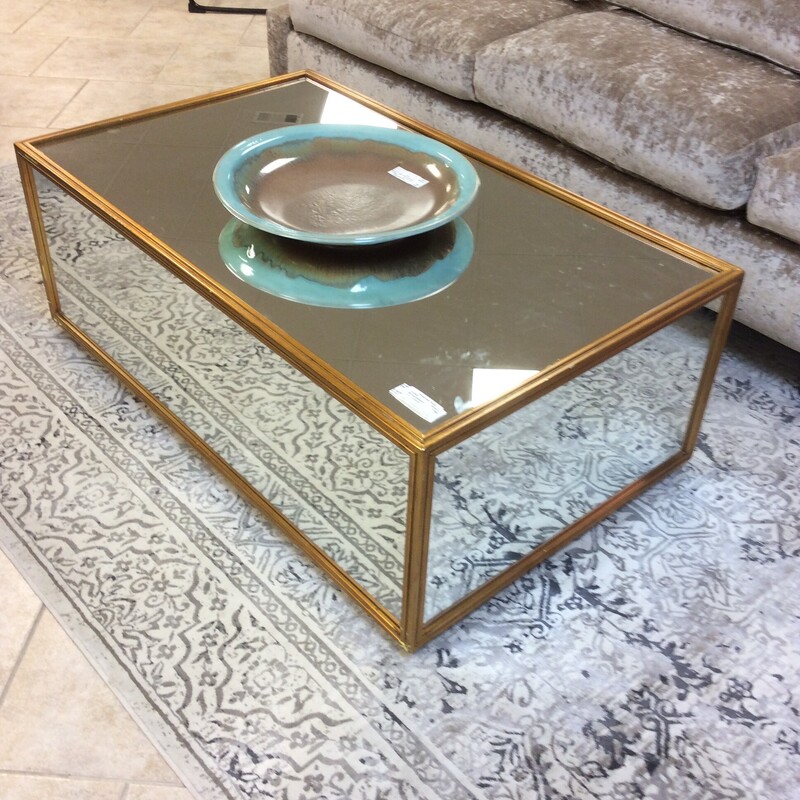 This high style coffee table has a mirrored top and sides with a gold leaf frame.