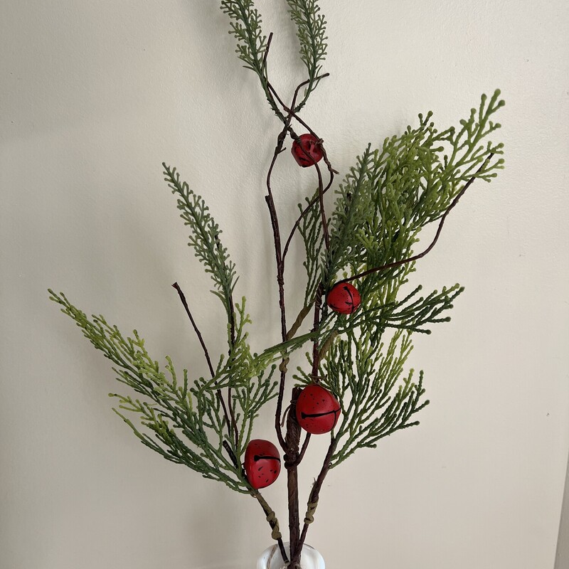 Bells Will Be Ringing Cedar branch is a decorative floral with a sturdy brown twig-like stem. It is filled with textured cedar greenery and features a cluster of antiqued red jingle bells.  Stem measures 17 inches long