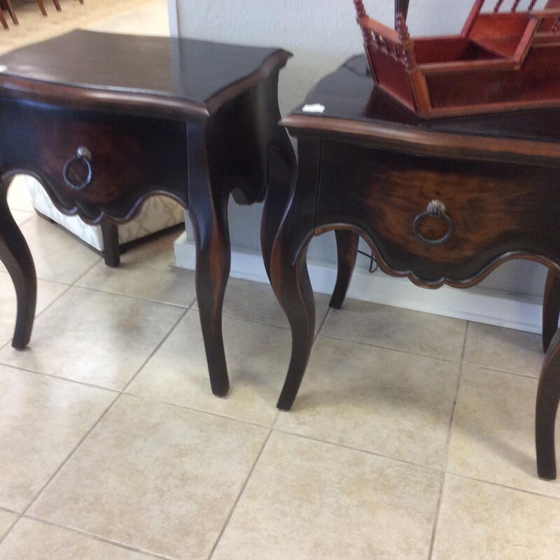 This pair of night stands have a distressed, black painted finish with natural wood showing through. They have cabriol legs and rustic metal hardware.