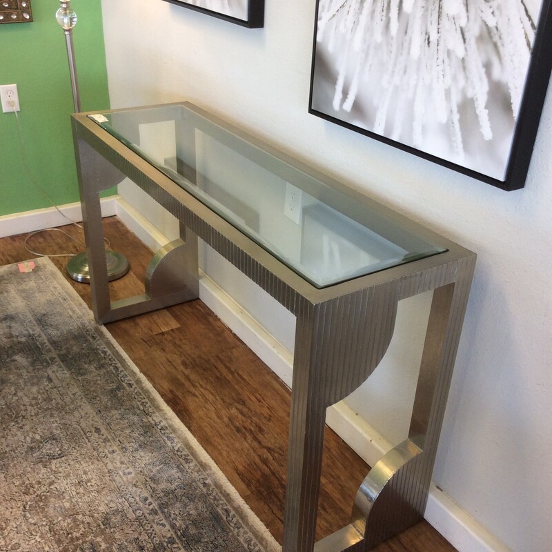 This contemporary style console table has a silver metal finish and a geometric design.