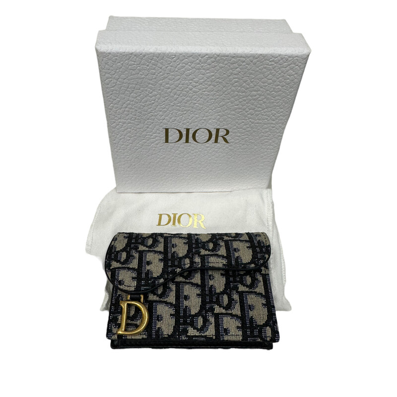 CHRISTIAN DIOR Oblique Saddle Card Holder in Blue. This stylish cardholder is crafted of blue on beige Dior monogram canvas. The wallet features a saddle-style frontal flap with a brass Dior D charm. This opens to a partitioned blue leather and fabric interior with card slots<br />
Dimensions:<br />
Base length: 4.25 in<br />
Height: 3.25 in<br />
Width: 0.75 in.
