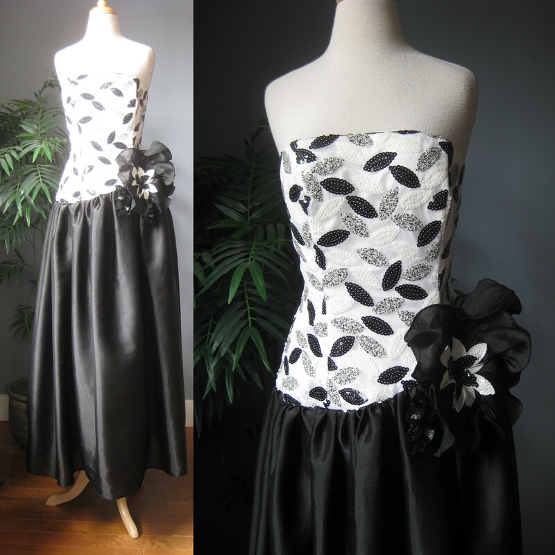 A dramatic gown  by Eugene Alexander from the 80s 90s.
Body conforming sequined strapless bodice in black and white.
Very full satin skirt that begins at the hips for that dropped waist silhouette so popular in that time.
Very high quality and quite heavy.
The dress has a built in crinoline under the skirt


The 3D Flowers and embellishments at the waist are tacked on and can easily be removed if desired. And repurposed!
Made in the USA
Marked size 12 - but probably best for a size M pls use the measurements here as your ultimate guide
Here are the flat measurements please double where appropriate:
armpit to armpit:  16.25  bodice is boned and shaped at the bust, you need it to be tight here to help hold it up.
waist: 15.5
hip: up to 33 super ful here, not supposed to be close to the body
Length from cetner of bodice to hem:  53
Thank you for looking!
#68376