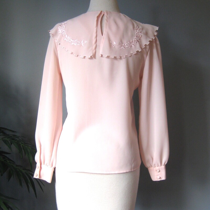 Vtg Josephine Secretary, Pink, Size: 10<br />
Sweet blouse with long sleeves with button cuffs and an embroidered capelet collar<br />
The little cape goes across the front, over the shoulders and meets at the center back where the shirt closes with a button and elastic loop.<br />
The capelet has a 'dentil' shaped edge and tonal satin stitch floral embroidery.<br />
It's by Josephone madein Korea<br />
no fabric id but it's certainly a polyester, no stretch<br />
Flat measurements:<br />
Shoulder to shoulder: 14.5<br />
Armpit to Armpit: 18.75<br />
Waist: 19<br />
length: 21<br />
underarm sleeve seam: 17<br />
<br />
excellent condition, two tiny spots, one on the edge of the capelet and one on one of the cuffs as shown.<br />
<br />
thank for looking!<br />
#2411