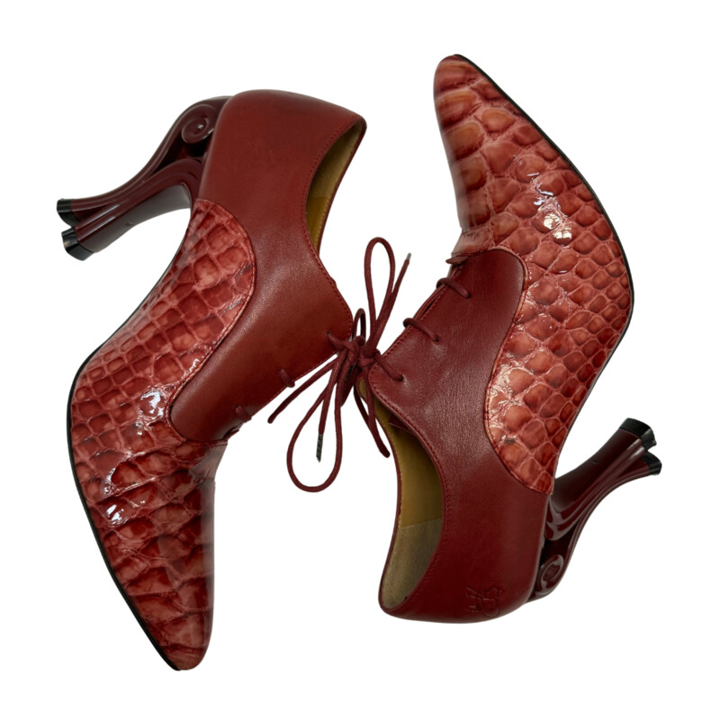 John Fluevog Ursula Lace Up Heel<br />
<br />
The Ursula bares an utterly divine, reptilian embossed patent leather that adorns the front of the foot. Crafted in Portugal, they feature tunite soles and that unmistakable 4 scrolled heel.<br />
<br />
Color: Red<br />
Size: 9