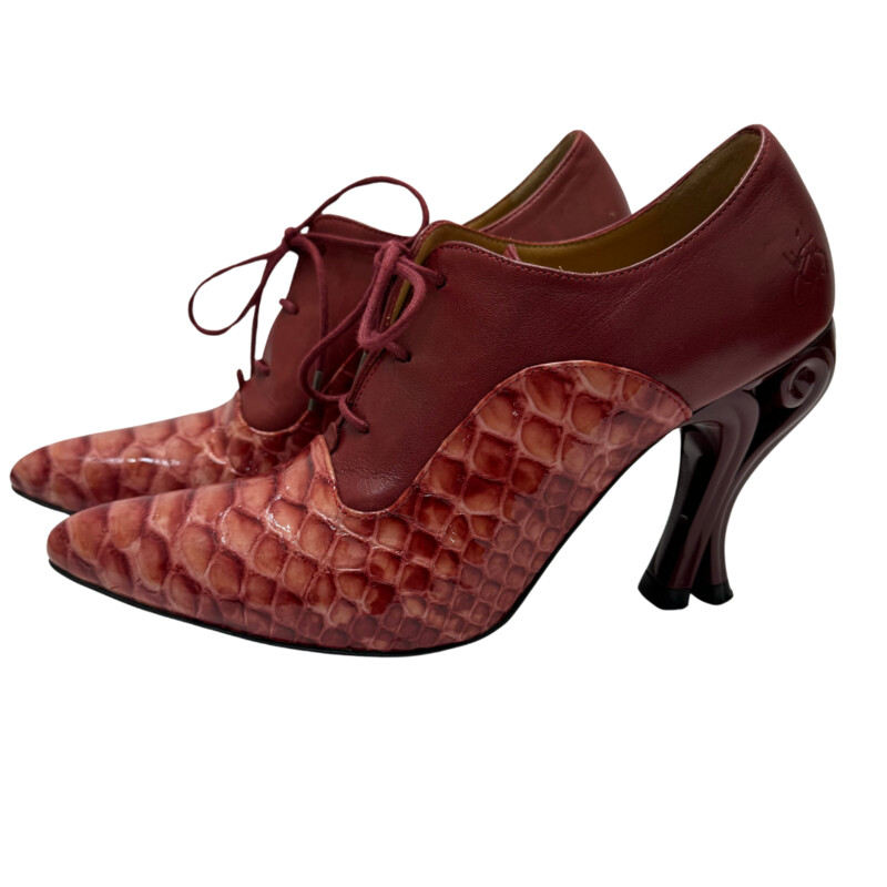 John Fluevog Ursula Lace Up Heel<br />
<br />
The Ursula bares an utterly divine, reptilian embossed patent leather that adorns the front of the foot. Crafted in Portugal, they feature tunite soles and that unmistakable 4 scrolled heel.<br />
<br />
Color: Red<br />
Size: 9