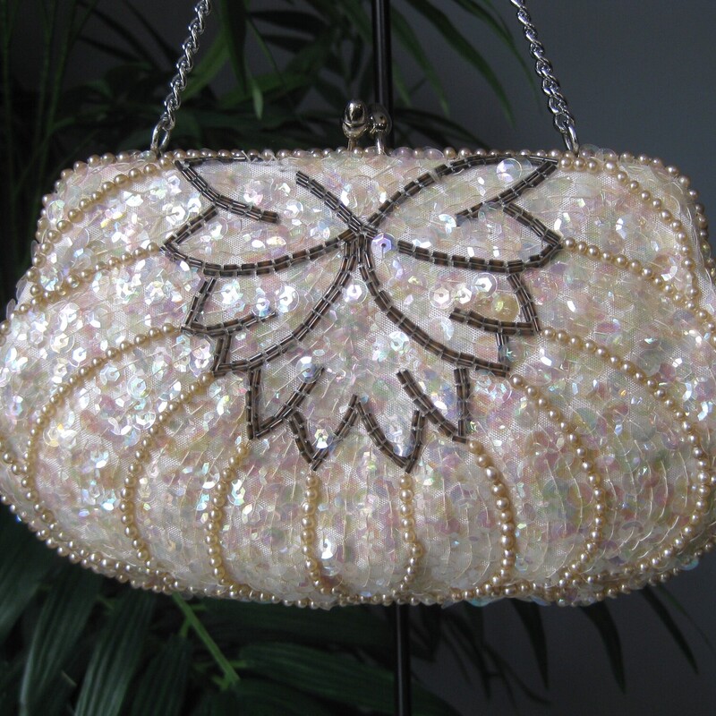 Vtg Japanese Beaded, Ivory, Size: N<br />
Sweet little sequined clutch by from the 1950s with a chain strap and kisslock freame.<br />
Made in Japan<br />
covered with irridescant clear sequins, silver beads and pearls in an art deco style design.<br />
White satin interior<br />
<br />
Measurements:<br />
Width: 8.25<br />
Height: 4.75<br />
when empty<br />
strap drop: 5<br />
<br />
<br />
Thank you for looking.<br />
#65828