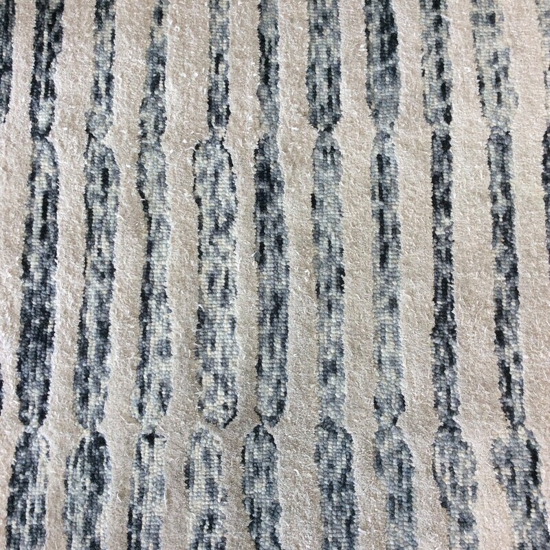This nice, contemporary area rug is by Nikki Chu. It features an abstract pattern of black, gray, cream and white.