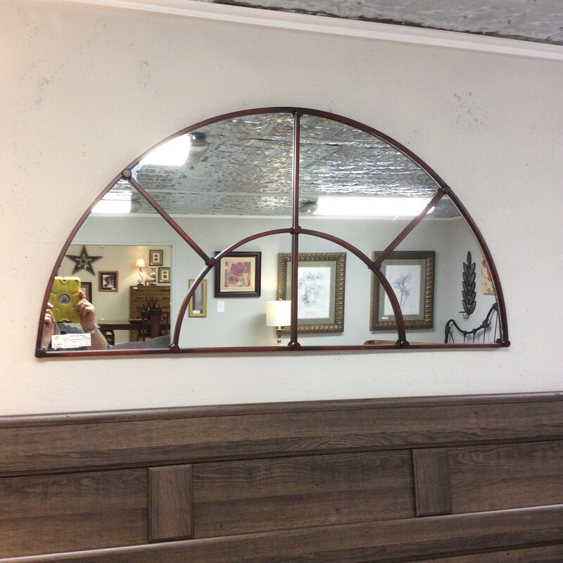 This arched  mirror has an antiqued copper metal frame.