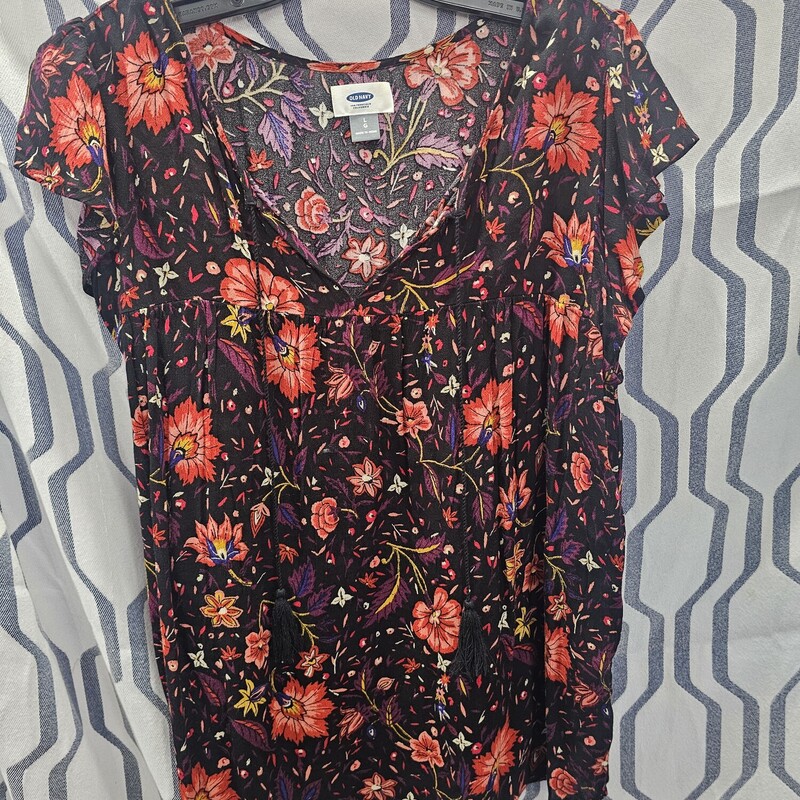 Cute cap sleeve blouse in black with burgandy, pinks whites, yellows and pinks in the floral design. It has a bit of a boho chic vibe and tassled ties for the collar.