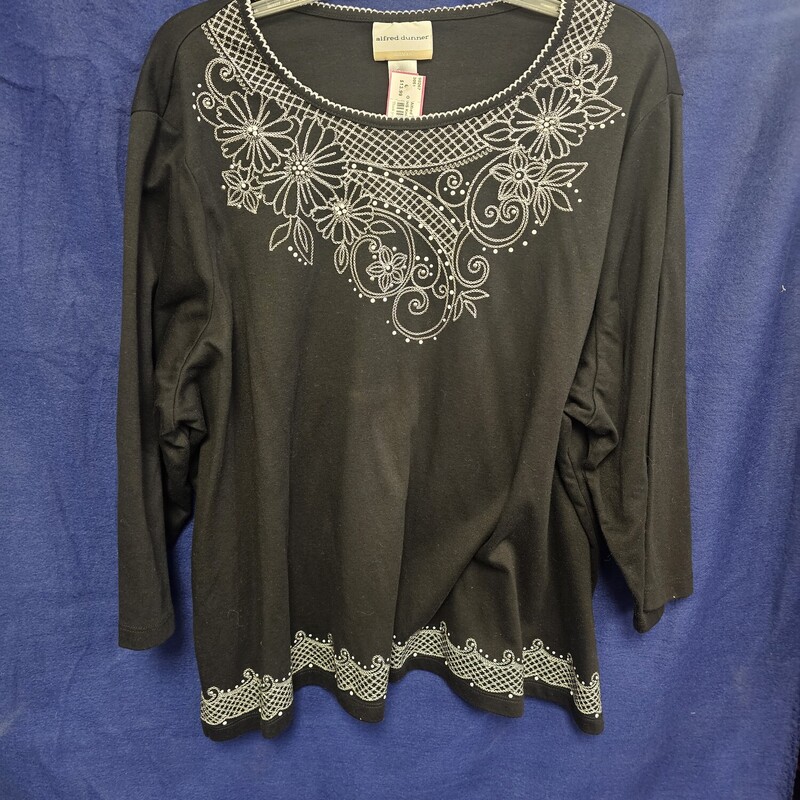 Half sleeve knit top in black with white embroidered floral design and beading.