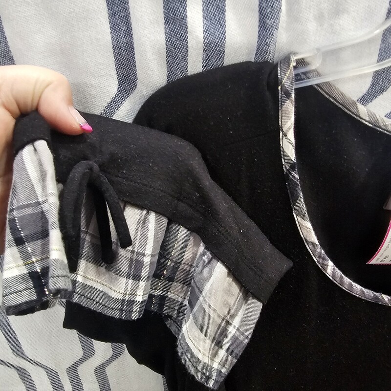 Half sleeve knit top in black with layered look sewn into the cuffs and hem in a grey plaid