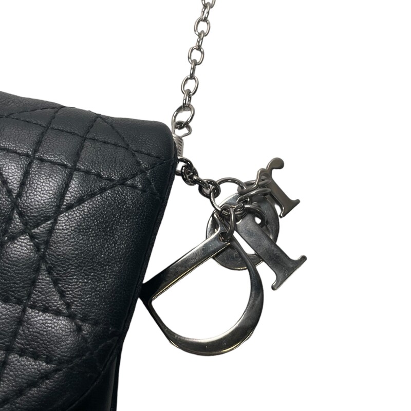 CHRISTIAN DIOR Cannage Quilted Cross Body Bag in Black. This stylish cross-body bag is crafted of geometric quilted cannage leather. The bag features a silver cross-body chain link strap and a facing flap that opens to a satin interior with room enough for day or evening essentials with the classic chic only from Christian Dior!<br />
<br />
Dimensions: 8.5W x 5H x 1D<br />
22 strap drop