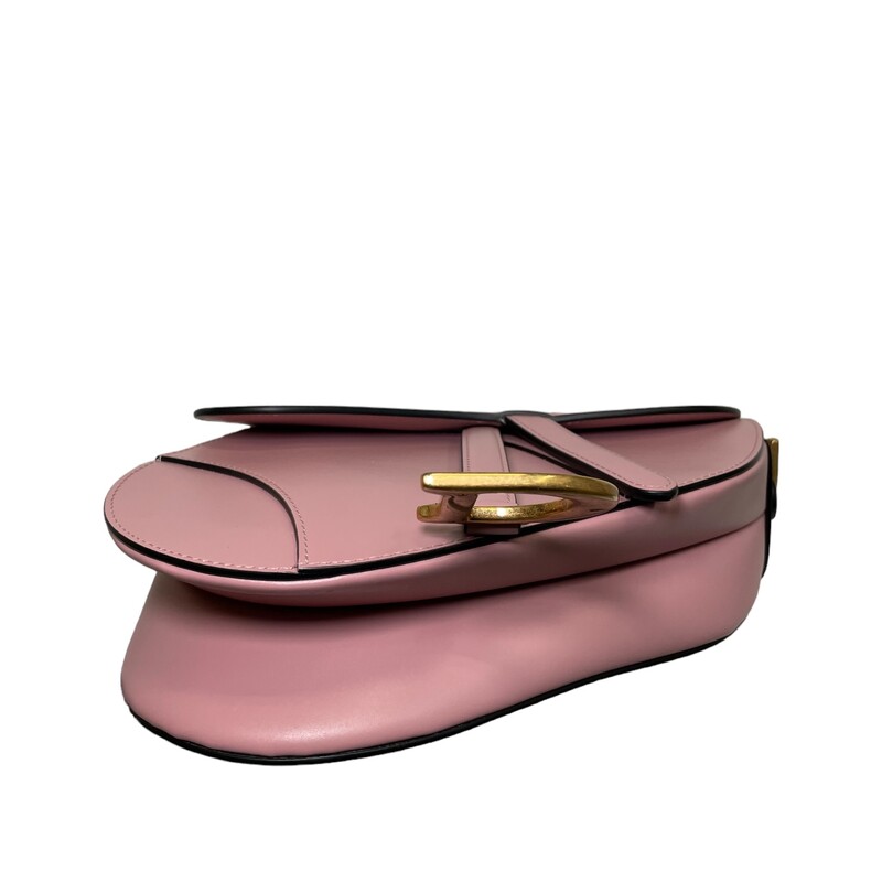Dior Saddle Bag With Strap<br />
Crafted in antique pink ultra-smooth calfskin, the legendary design features a Saddle flap with a magnetic D stirrup clasp with pulls as well as an antique gold-finish metal CD signature adorned with tonal leather on either side of the strap. Equipped with a thin, adjustable and removable shoulder strap, the Saddle bag may be carried by hand, worn over the shoulder or crossbody<br />
Color: Anitque Pink<br />
Date code: 05-RU-0263<br />
Dimensions: Medium<br />
10 x 8 x 2.5 inches (Length x Height x Width)<br />
Handle drop length: 7.5 inches