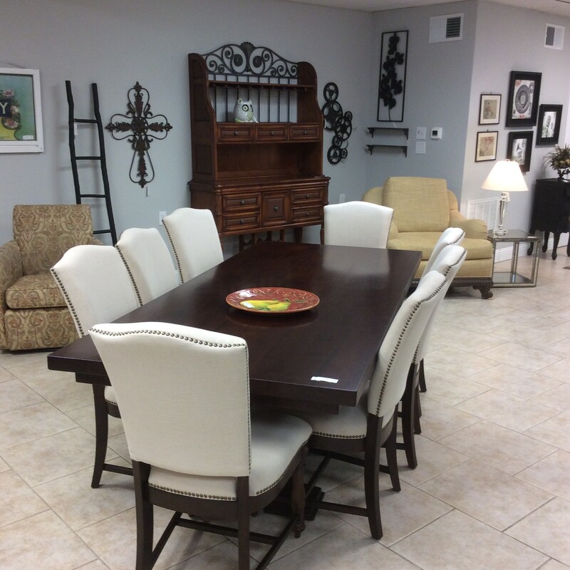 This is a very nice diningroom set. The table has a dark wood finish and the 8 chairs have been upholstered in cream with a bold nailhead trim.
