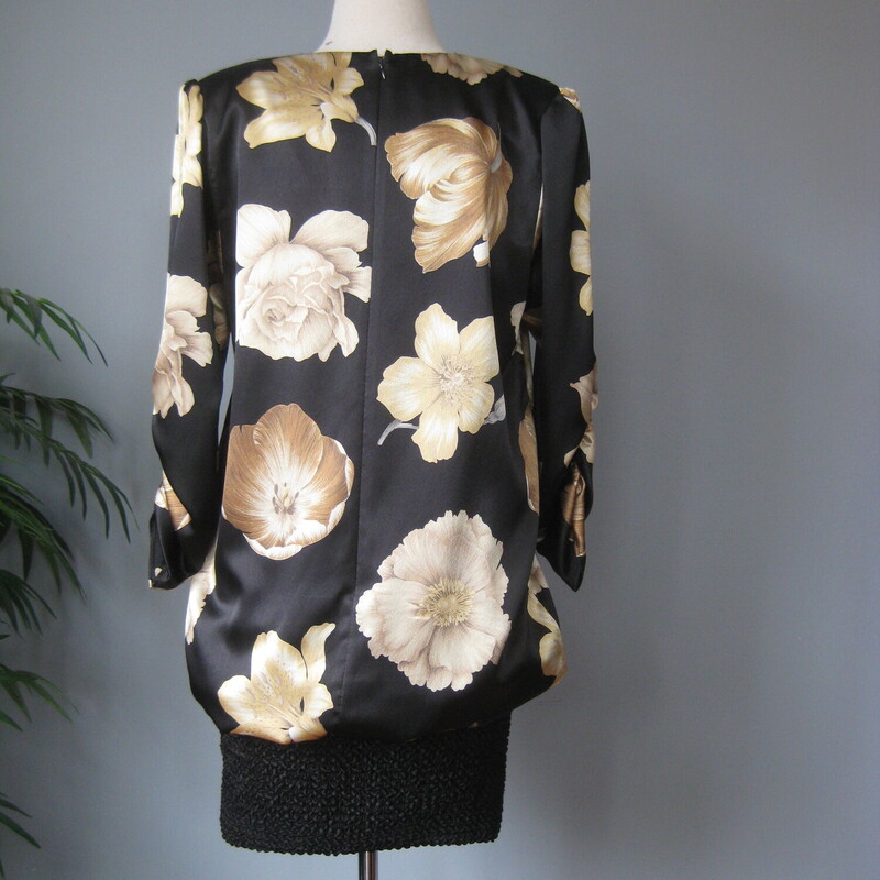 Vtg Siasia Silk Flower, Blk/gold, Size: 8
Fun 1980s dress featuring a drapey satin top that blouses over a tight short skirt made of a stretchy bubble fabric.
The top has beautifully rendered large soft gold flowers.
Big shoulder pads
ruched elbow length sleeves (very 80s!) with puffed shoulders
v neck
by Sciasia
Flat measurements:

Shoulder to shoulder: 16
Armpit to armpit: 20
Waist: 21 it is totally not fitted to the body here
Hips: 19  very stretchy here
Underarm sleeve seam length: 15.5
Length of dress: 38

Thanks for looking!
#69136