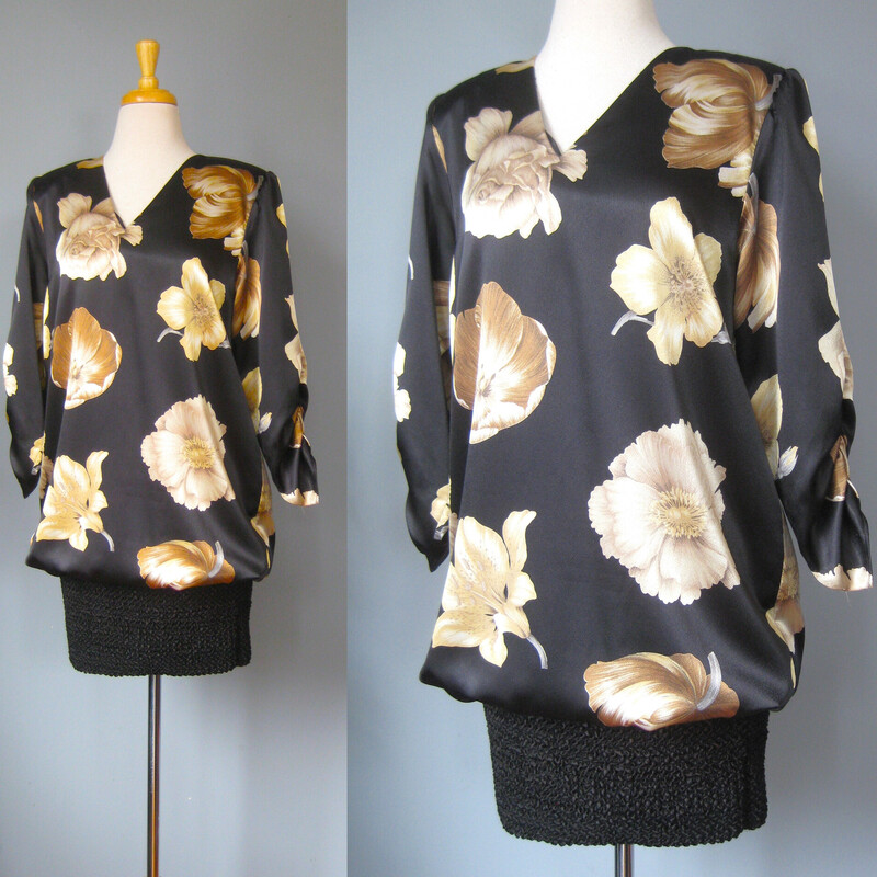Vtg Siasia Silk Flower, Blk/gold, Size: 8
Fun 1980s dress featuring a drapey satin top that blouses over a tight short skirt made of a stretchy bubble fabric.
The top has beautifully rendered large soft gold flowers.
Big shoulder pads
ruched elbow length sleeves (very 80s!) with puffed shoulders
v neck
by Sciasia
Flat measurements:

Shoulder to shoulder: 16
Armpit to armpit: 20
Waist: 21 it is totally not fitted to the body here
Hips: 19  very stretchy here
Underarm sleeve seam length: 15.5
Length of dress: 38

Thanks for looking!
#69136