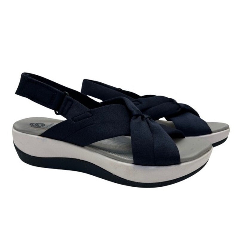 NEW Cloudsteppers by Clark Arla Belle Sandals<br />
Color: Navy<br />
Size: 5.5<br />
Flexible crisscross straps with knotted detail, adjustable hook-and-loop backstrap<br />
Padded insole, EVA midsole, textured outsole<br />
Bottom construction: Arla<br />
Approximately 1-5/8H heel<br />
Fit: true to size<br />
Fabric upper; man-made balance